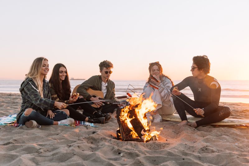 Friends at the beach sitting around a bonfire