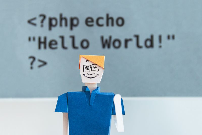 'Hello World!' code behind smiling man folded by paper