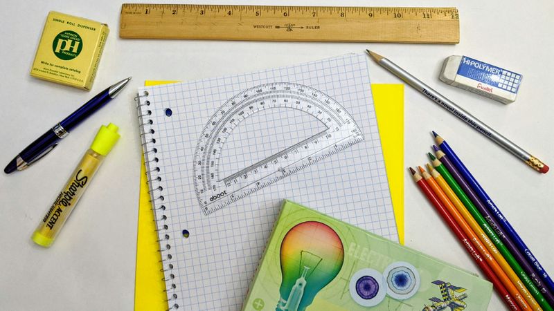 A math notebook, protractor, and other stationery on a desk.
