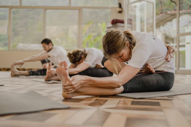 Three students taking a yoga class in a campus gym.