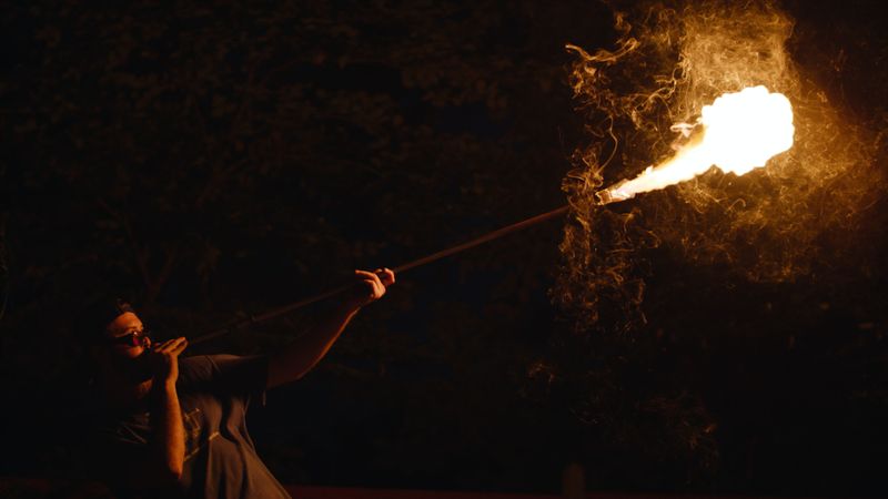 A person blowing fire out of a glass pipe