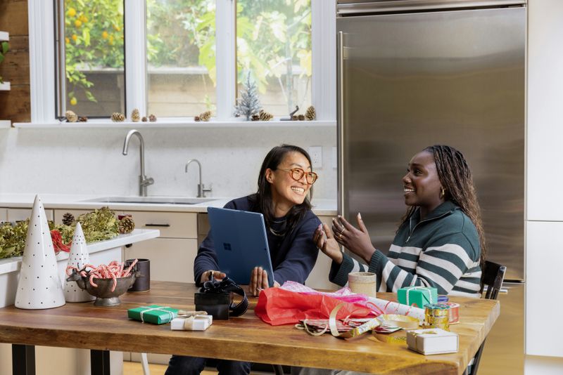 Two friends sitting at a kitchen table talking to each other.