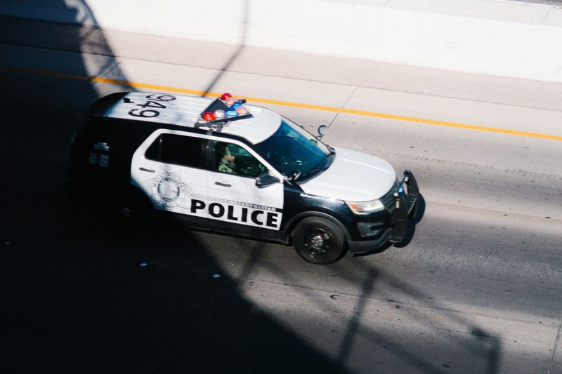 A police car on the road, its bottom half covered by shadows.