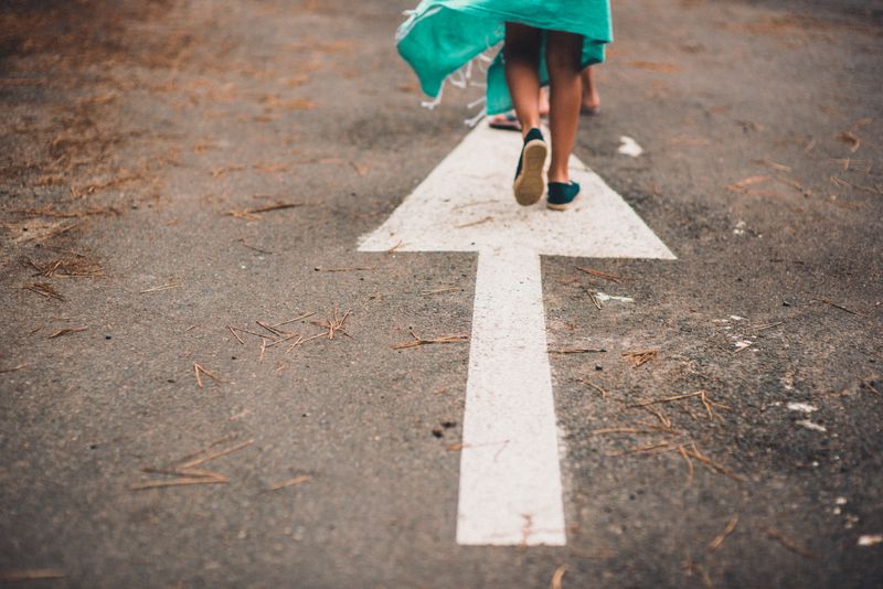 A person walking on a painted arrow along a path