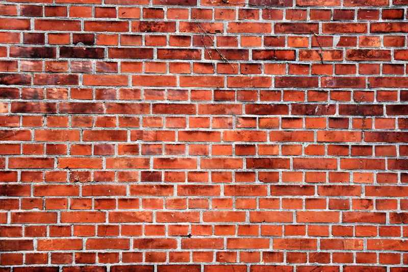 A worn out brick wall with some sticks hanging on it.