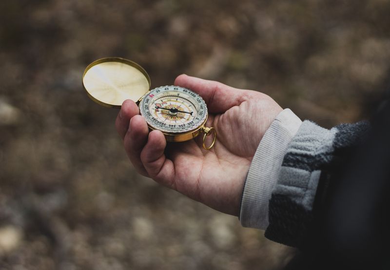 A hand holding a compass.