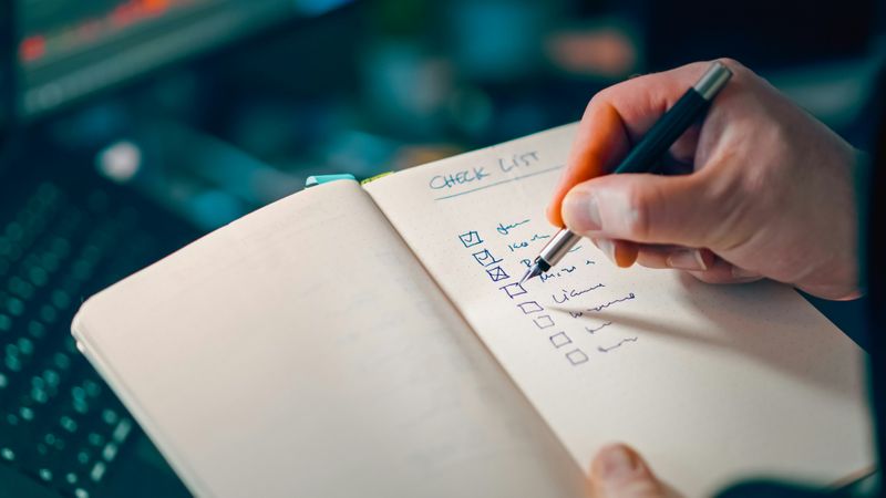 A person checking items off a checklist in a notebook.