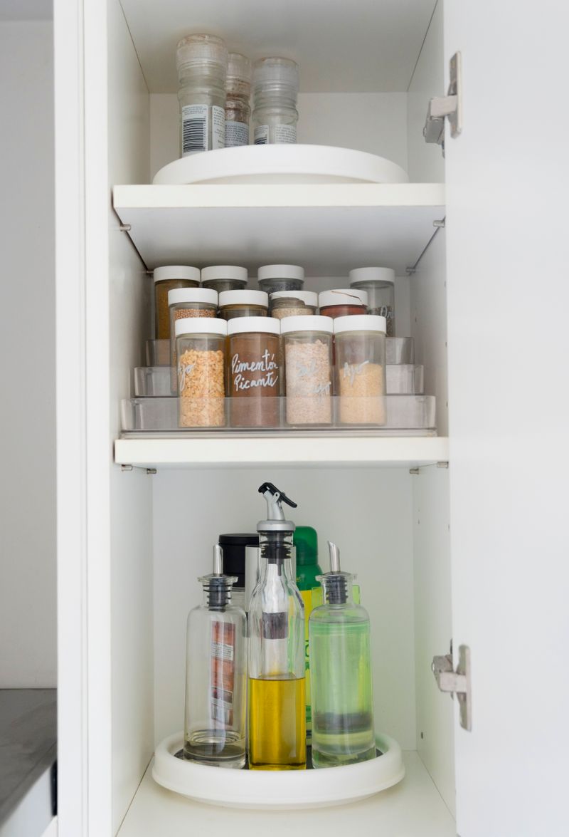 A kitchen cabinet. A spice organizer sits on the middle shelf.