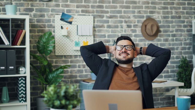 A young employee leans back in his desk.