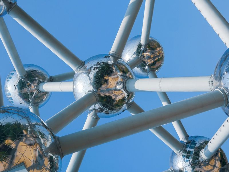 A metal model of atoms held together by bonds against a blue backdrop.