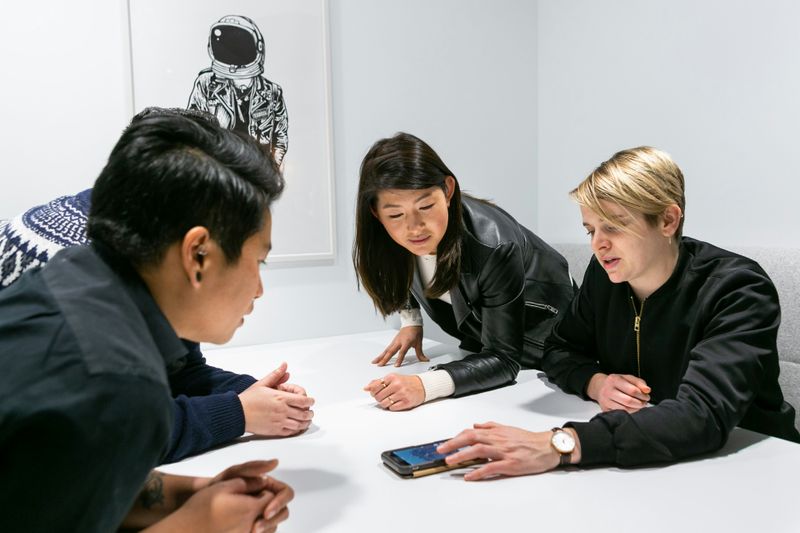 A group of office workers happily working together at a desk.