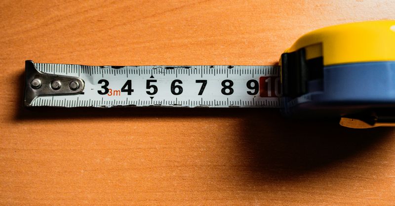 A tape measure being rolled out on a desk.