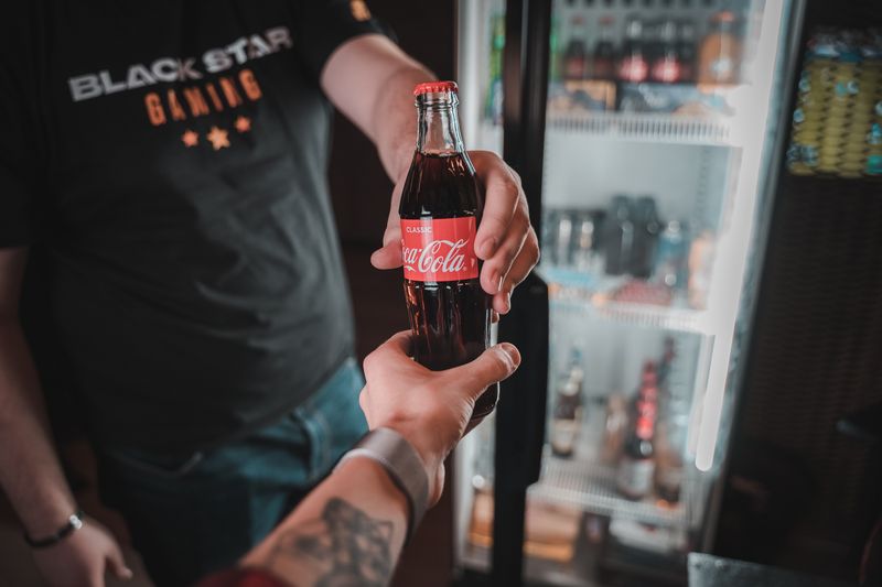 A man handing a Coca-Cola from a cooler to the person holding the camera.