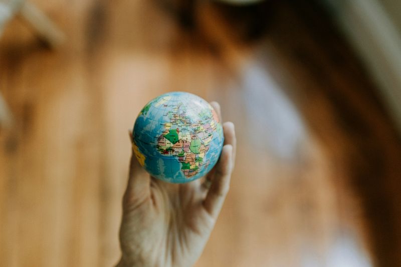 A hand holding a miniature globe with the continent of Africa highlighted