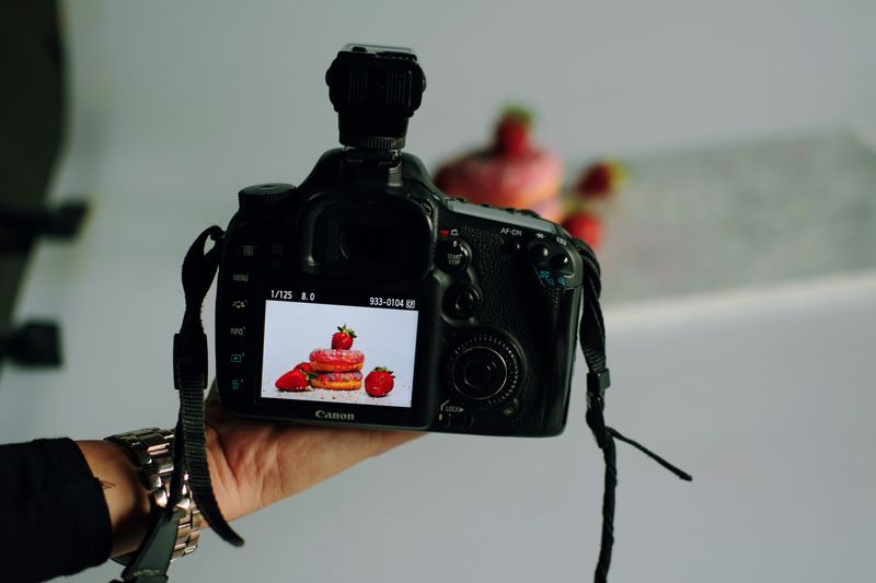 A camera taking a picture of strawberries and donuts.