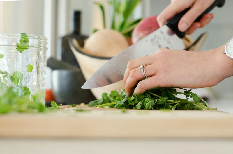 Hands chopping parsley on a cutting board.