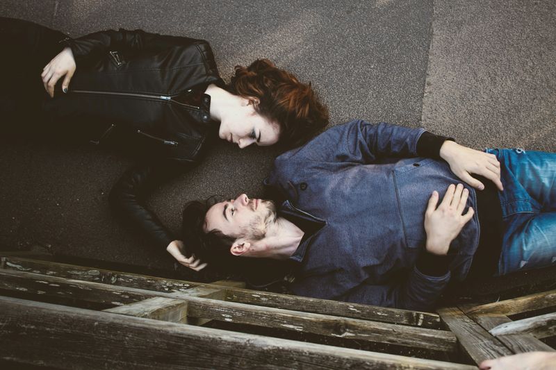 a birds-eye view image of a man and woman, lying parallel in different directions, but facing each other.