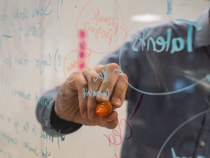 A teacher writing on a glass board.