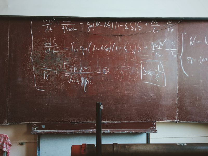 An empty school classroom with math equations on a chalkboard