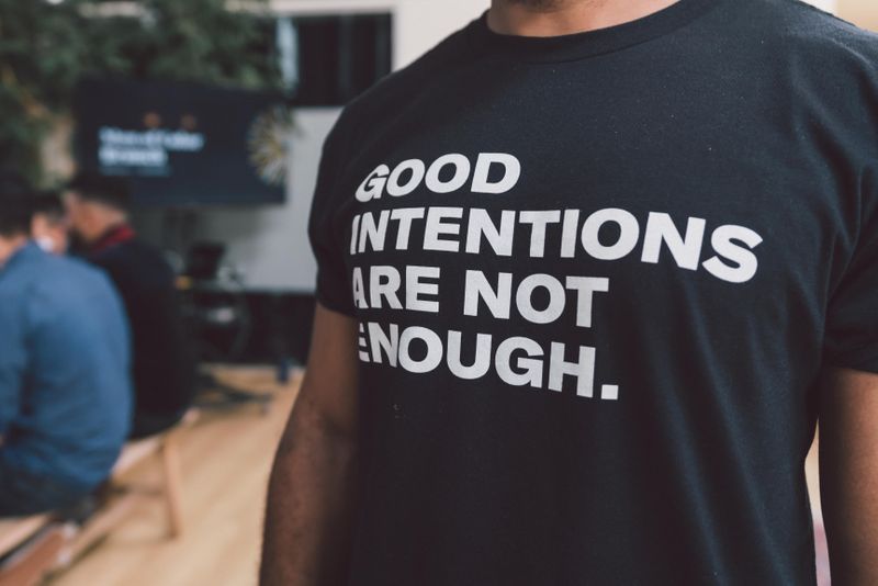 A person wearing a t-shirt with a message reading 'Good intentions are not enough.'