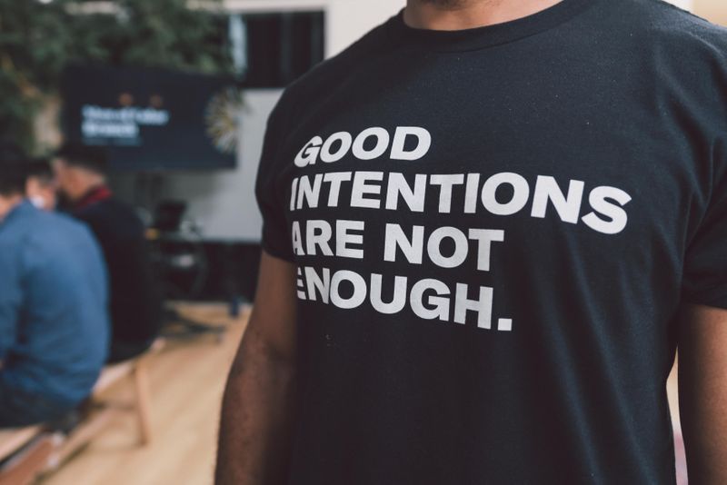 A person wearing a t-shirt with a message reading "Good intentions are not enough."