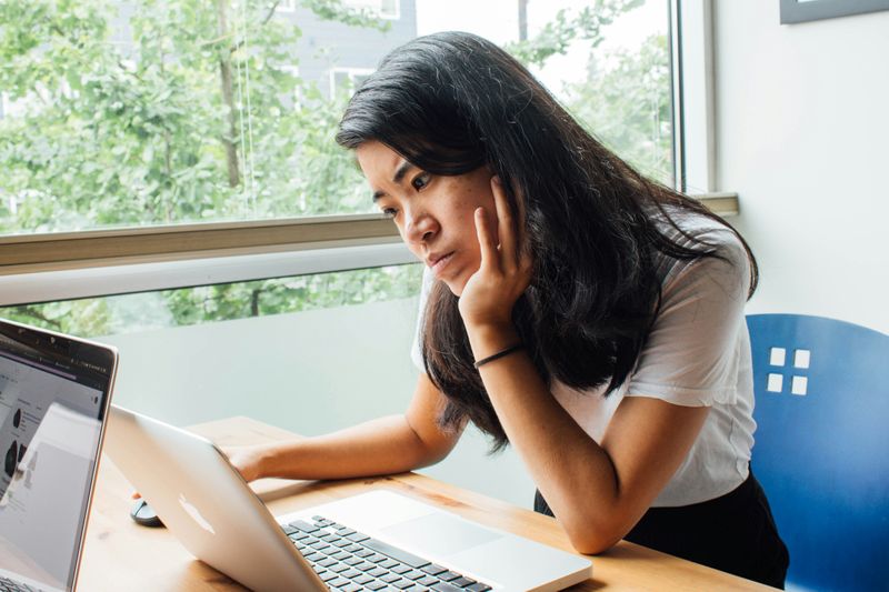 A worried woman looking at a laptop.