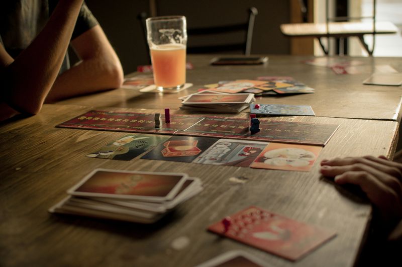Two people sitting in a cafe playing a board game on a wooden table.