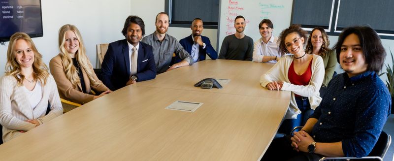 A group of diverse coworkers smile around a meeting table.