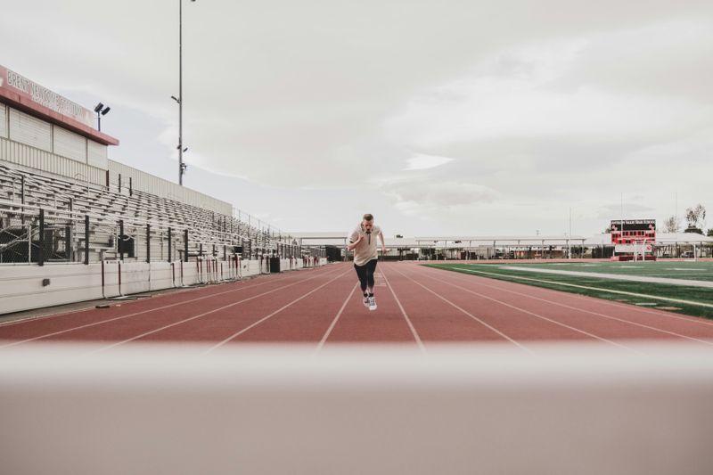 A person running toward the finish line on a track at a stadium.