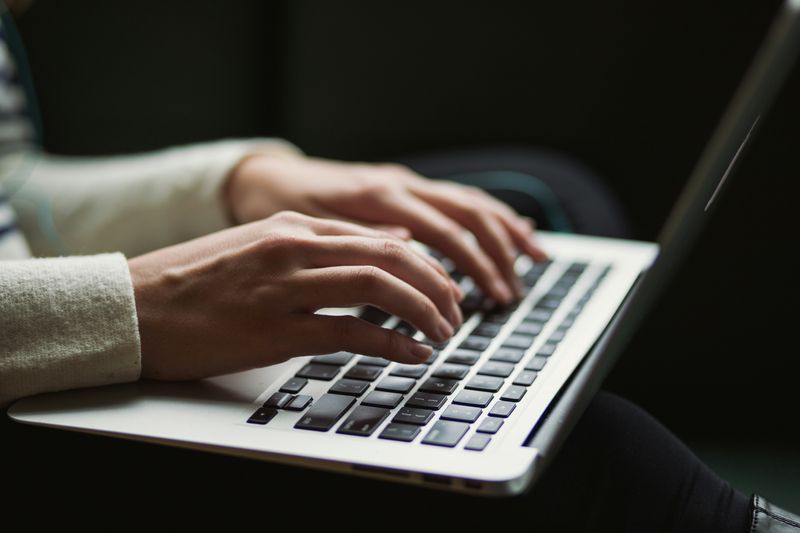 A woman's hands typing on a laptop keyboard.