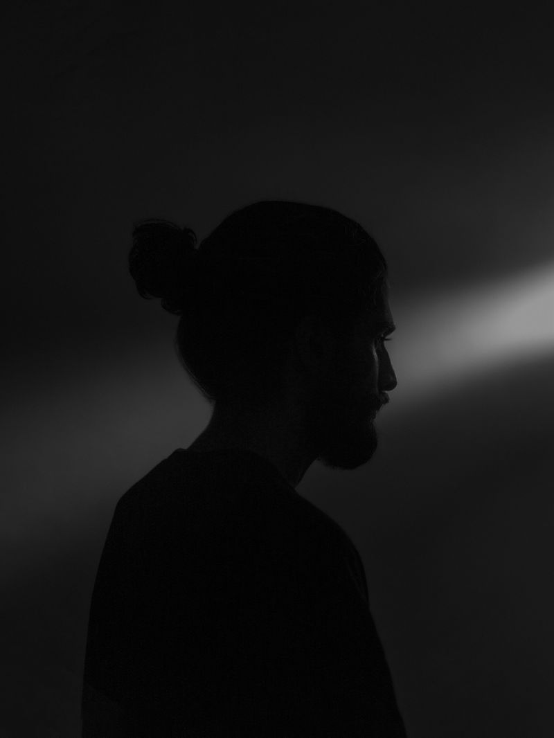 A man sitting alone in shadow.