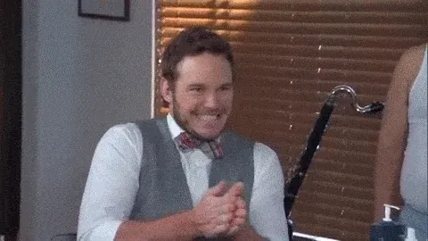 Chris Pratt looking excited with a grin while rubbing his hands together in anticipation.