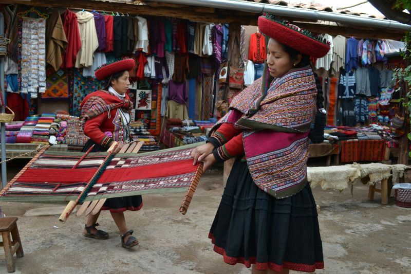 Indigenous people in a South American market weaving and selling traditional clothing.