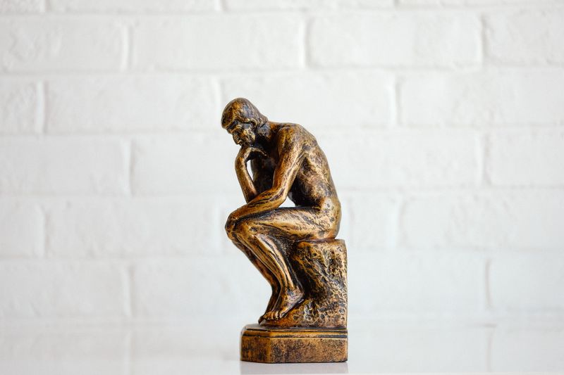 Statute of a man sitting down and thinking.