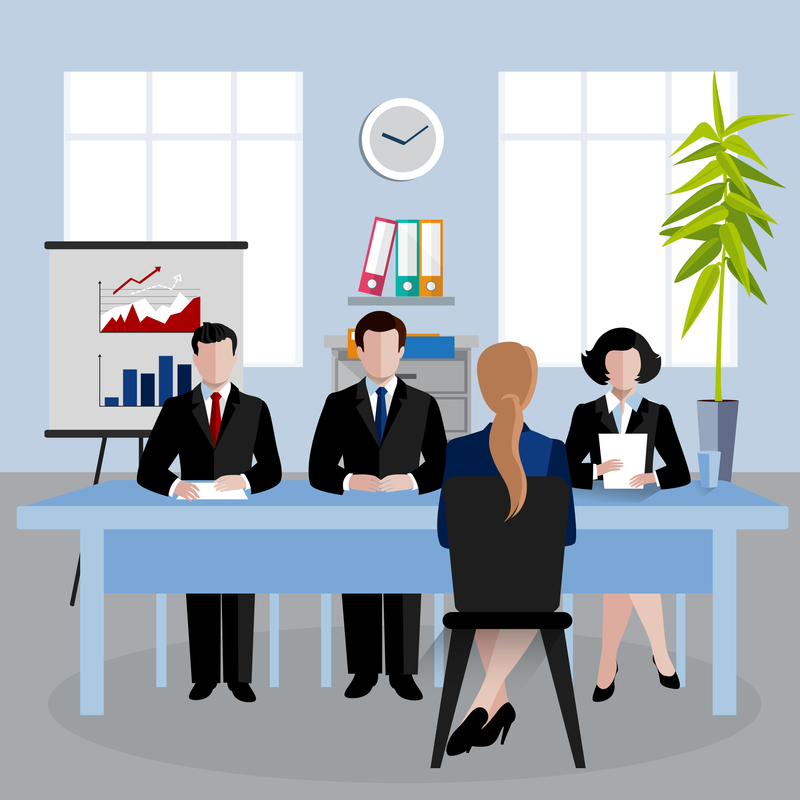 A woman in a business suit sits at a desk facing a panel of interviewers.