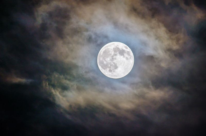 A moon in the clouds lighting up the sky.