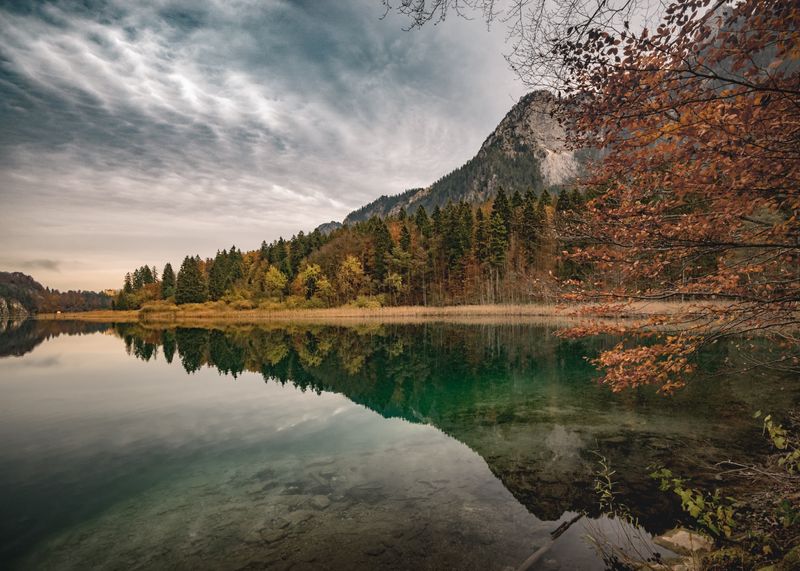 a beautiful landscape with a mountain and a lake. A part of the lake is the mirror image of the sky.