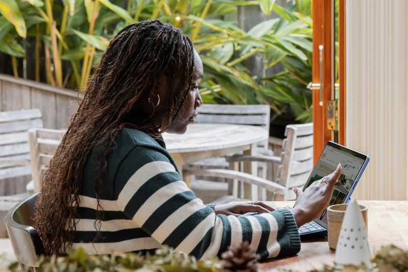 A person working on a computer from an outdoor lounge at their home.