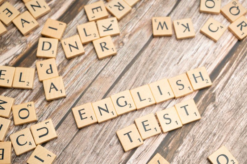 Scrabble letters scattered across a table, with some forming the phrase “English test.”