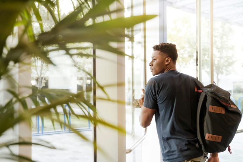 A Black male student walks through a school entrance.