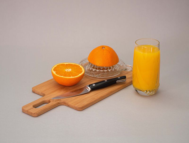 A graphic showing orange juice and a slice of orange behind a rush of water