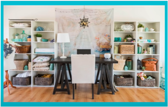 An open shelving unit with opaque baskets. A desk, laptop, and lamp are in the middle of the open shelving unit.  