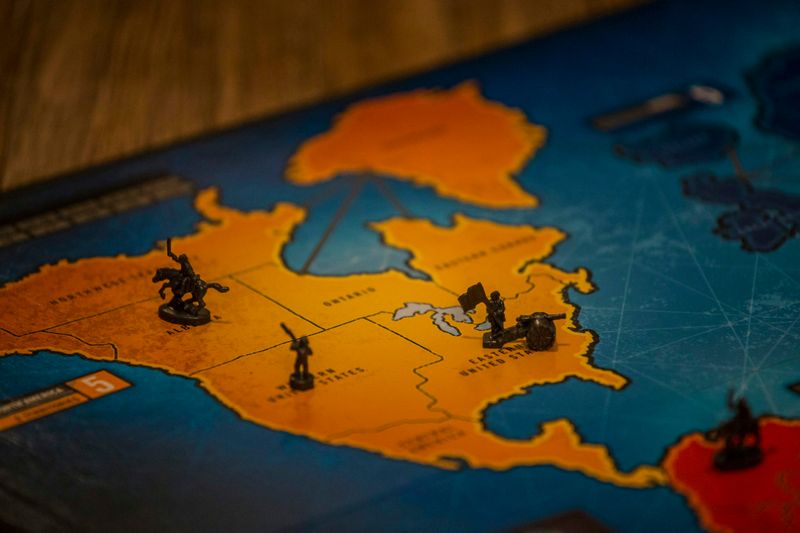 A war themed game board with pieces of small military characters on a North American map.