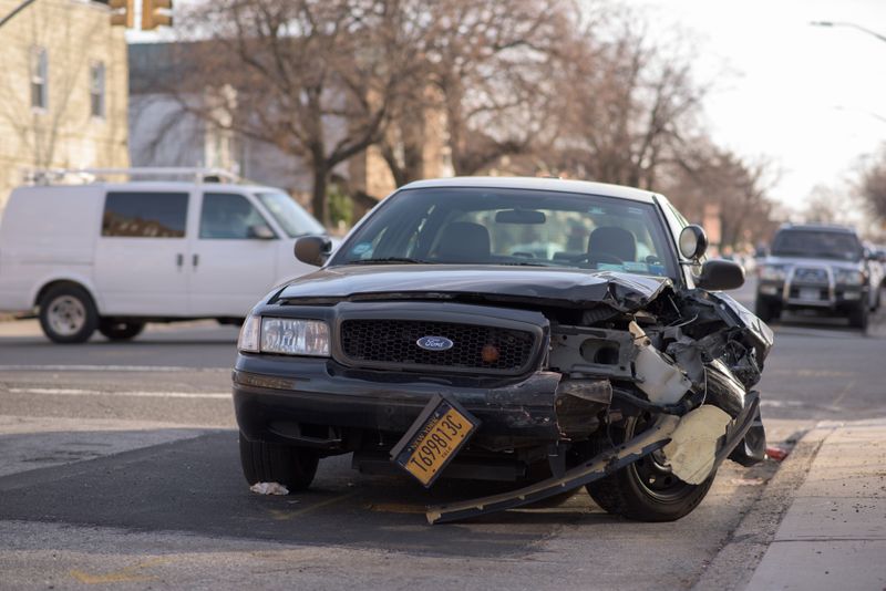 Black Ford with collision damage on the front left side of the car. 