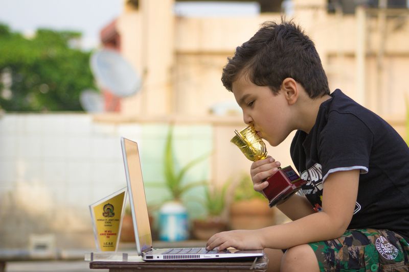 A young boy kissing a trophy.