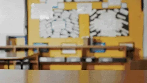 A classroom with a stack of books actively piling up representing education.