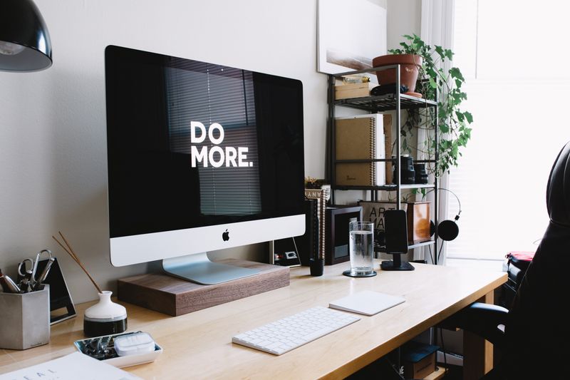 Apple computer monitor says 'Do More' with white text on a black background.