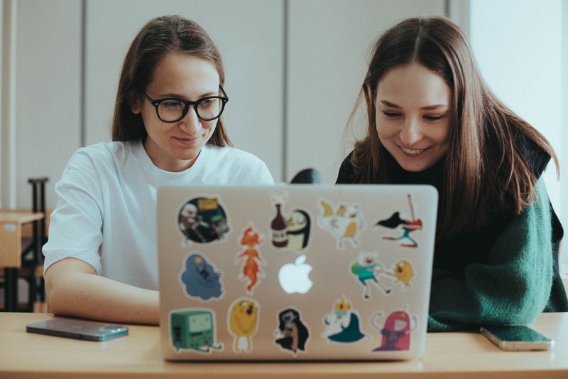 Two students at a laptop share their ideas.