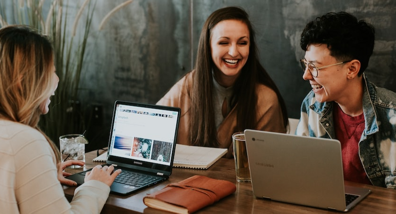 Group of coworkers laughing in front of their laptops.