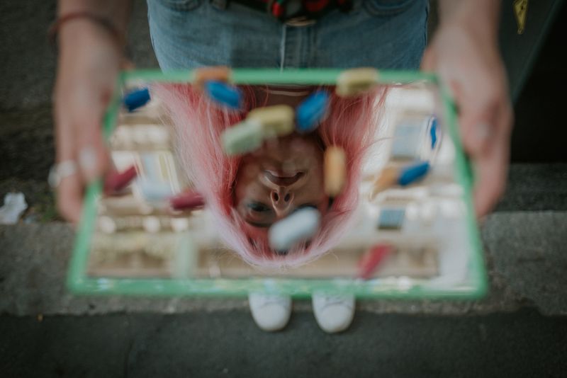 A person holding a small mirror with pills on it.